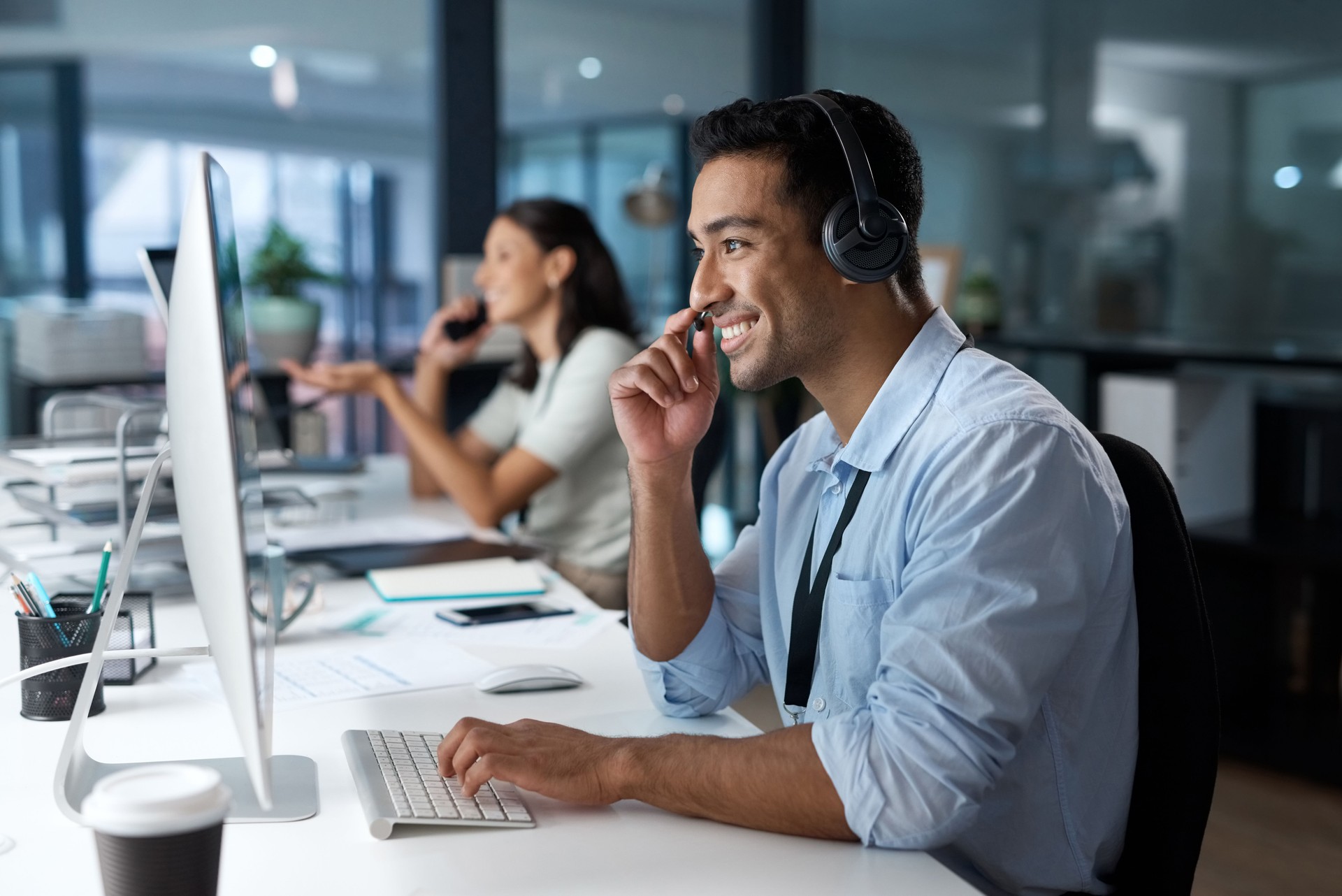 Plan d’un jeune homme utilisant un casque et un ordinateur dans un bureau moderne
